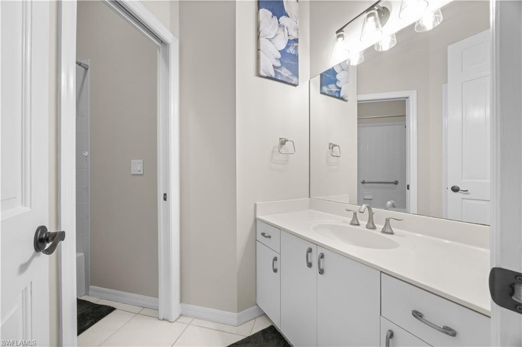 Bathroom featuring a vanity with a white countertop and sink, brushed nickel faucet, and an illuminated mirror
