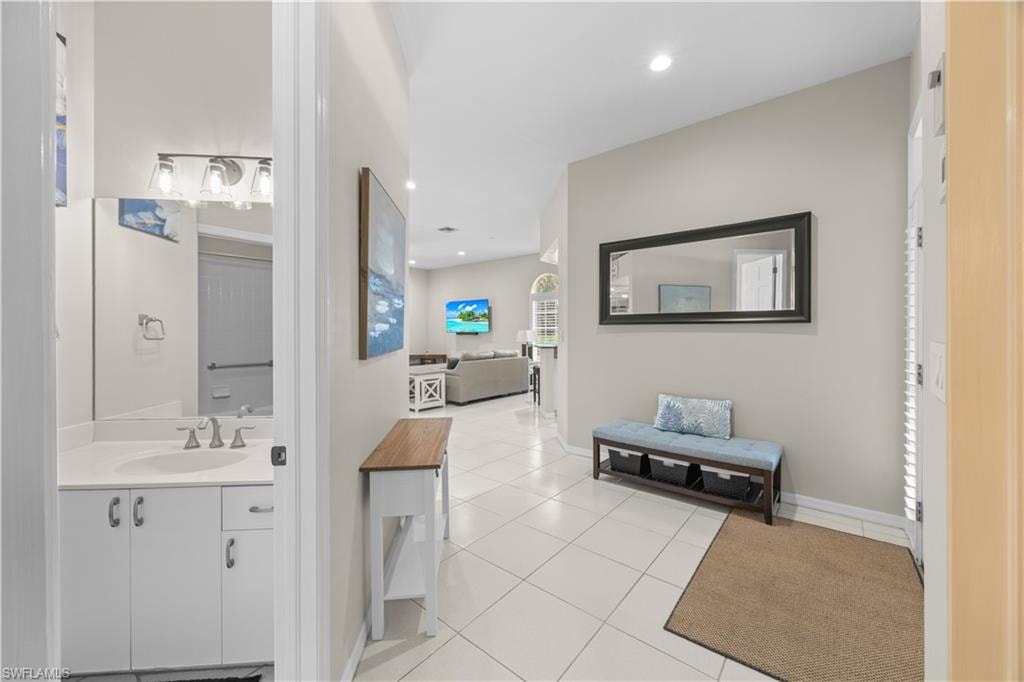 The property features a bright hallway with light-toned tiled flooring and recessed lighting