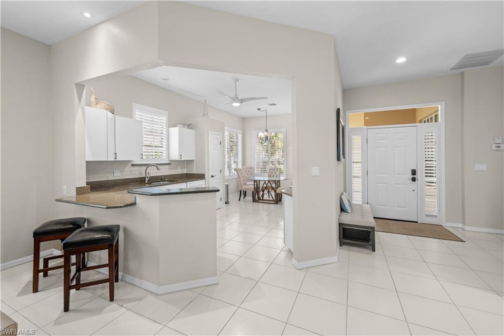 The property features an open-concept living area with tile flooring, a kitchen with white cabinetry and a breakfast bar, and a dining area with a chandelier