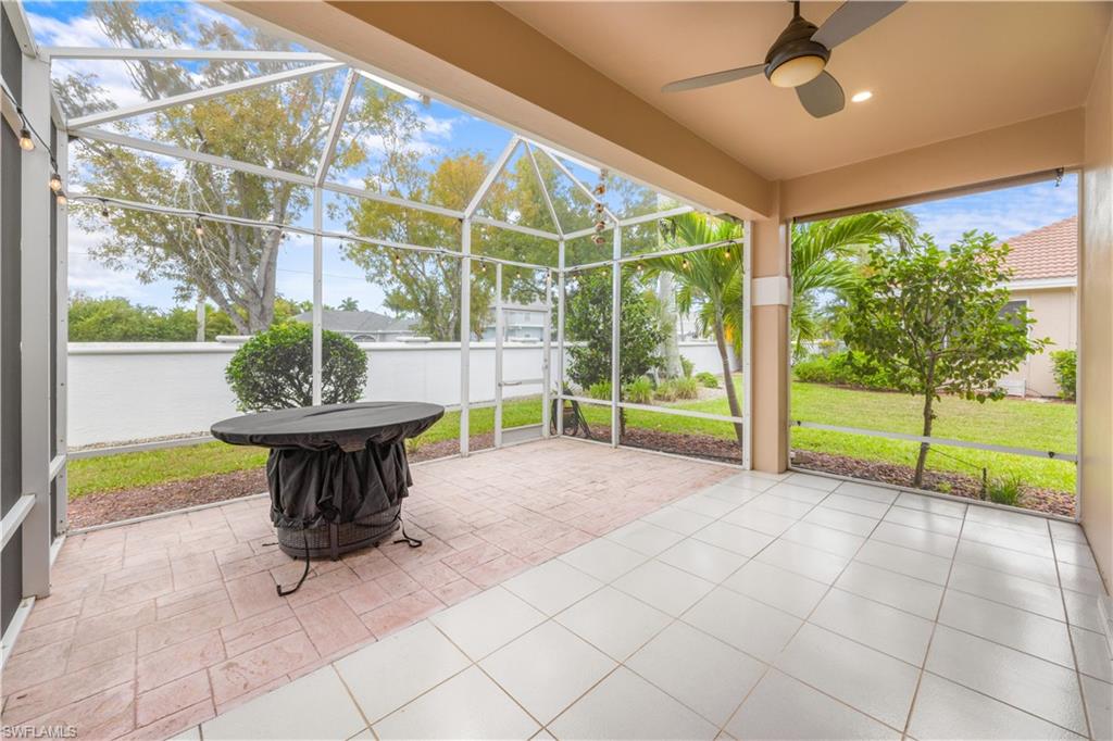 Spacious screened patio area featuring both tiled and paved sections, with a ceiling fan and outdoor string lights
