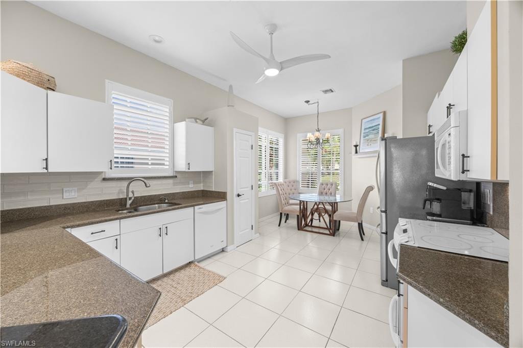 The kitchen features white cabinetry, stone countertops, a tile backsplash, and tile flooring