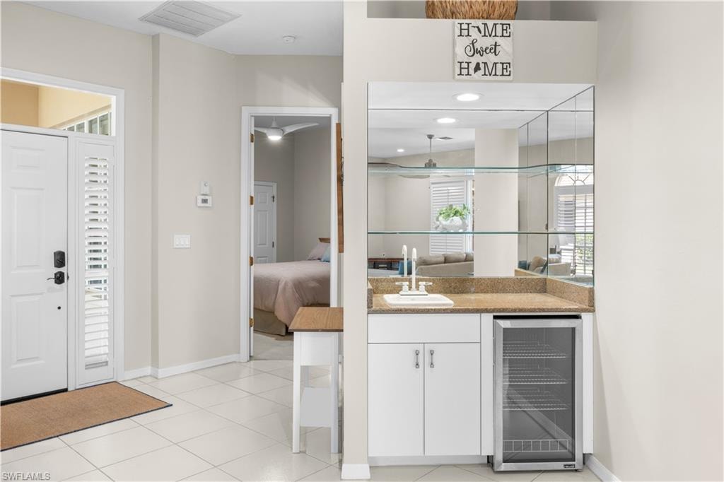 Entryway featuring white tiled flooring and a white front door with louvered side panels