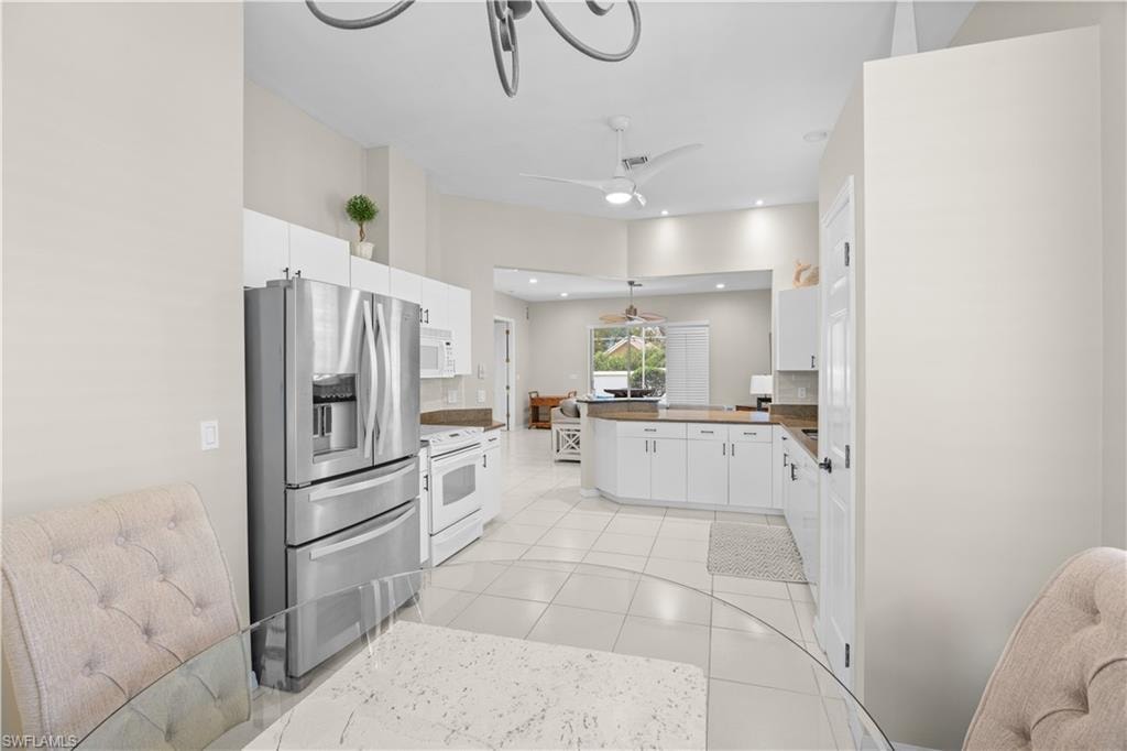 The kitchen features stainless steel appliances, white cabinetry, a tiled floor, and recessed lighting