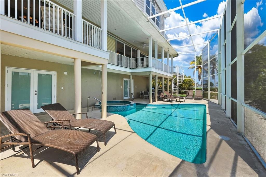 Screened pool enclosure featuring a curvilinear pool, integrated spa, and concrete decking