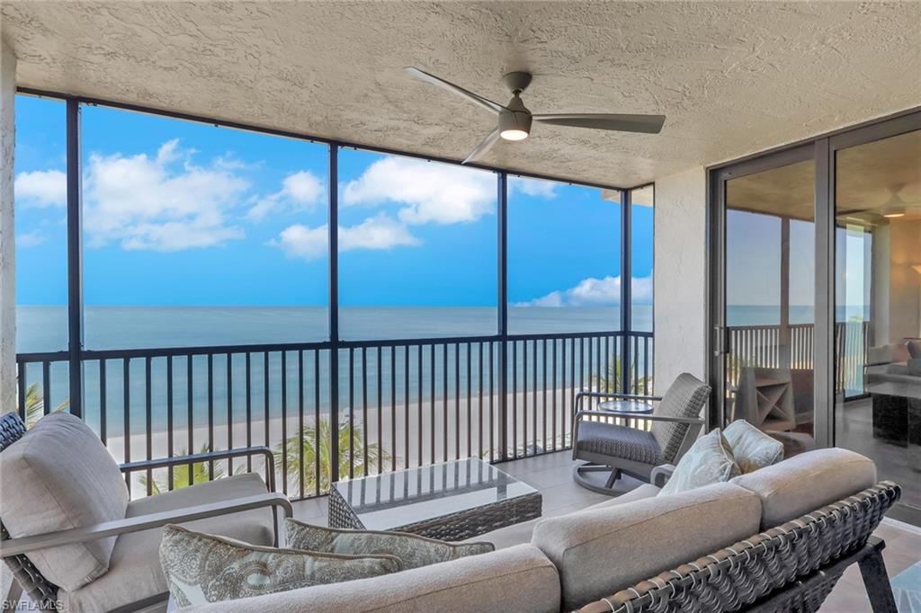 Expansive screened balcony featuring direct beach frontage, a contemporary ceiling fan, and sliding glass doors providing interior access