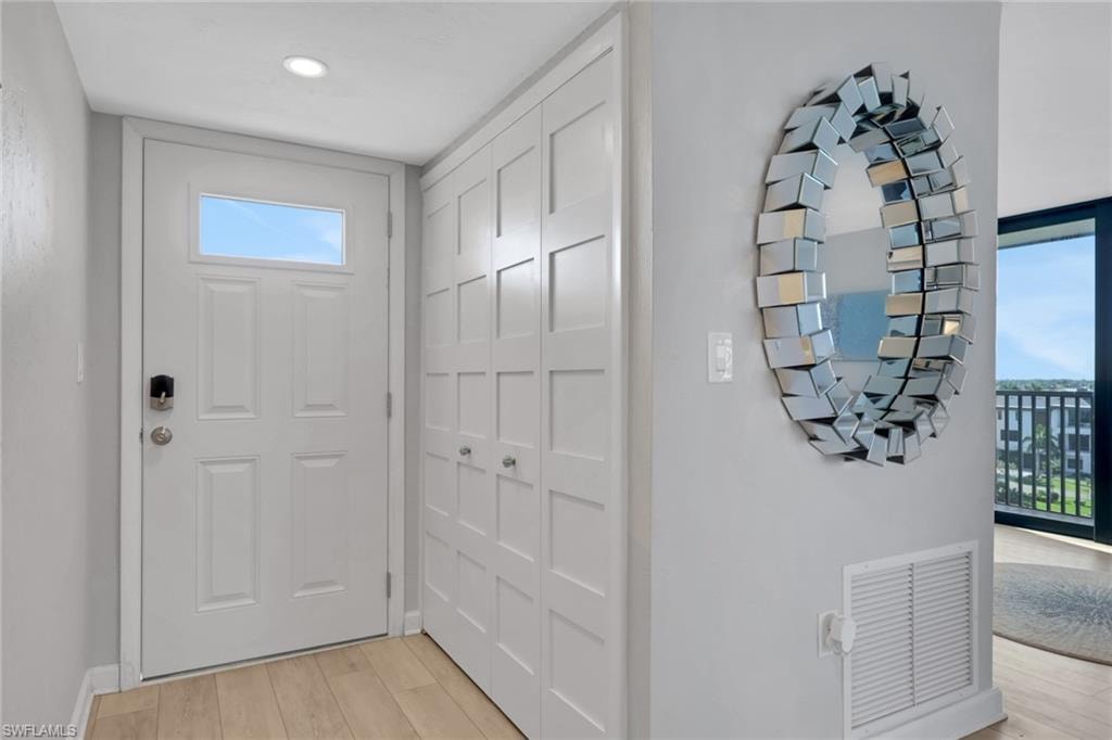 Entryway featuring light wood-finish flooring, a white paneled door with an upper glass insert, and recessed ceiling lighting