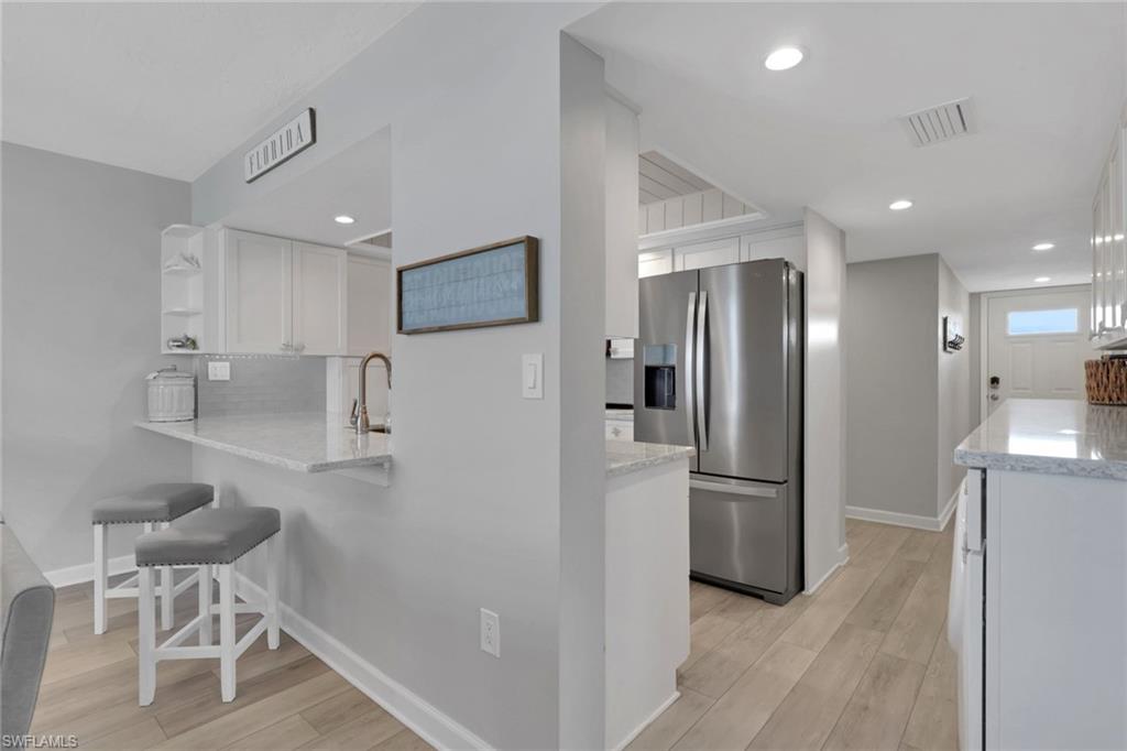 Kitchen passthrough with granite countertop, stainless steel faucet, and white shaker cabinetry
