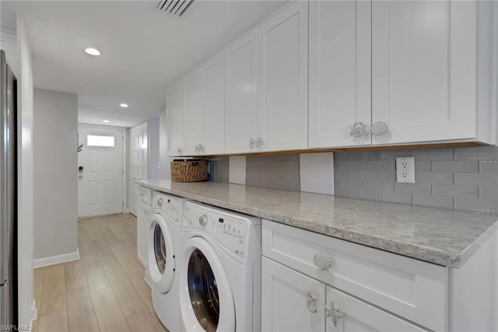 Dedicated laundry area featuring white shaker-style cabinetry, a light-toned countertop, and a gray subway tile backsplash