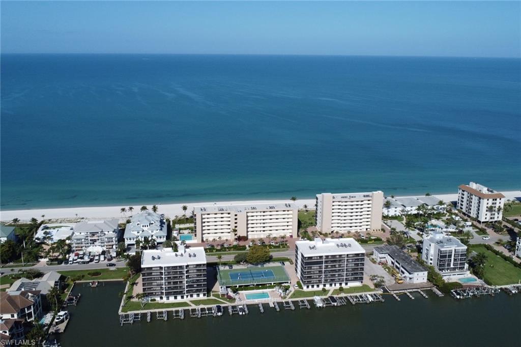 Coastal property featuring direct beach access, multiple residential buildings, private boat docks, a tennis court, and an outdoor swimming pool