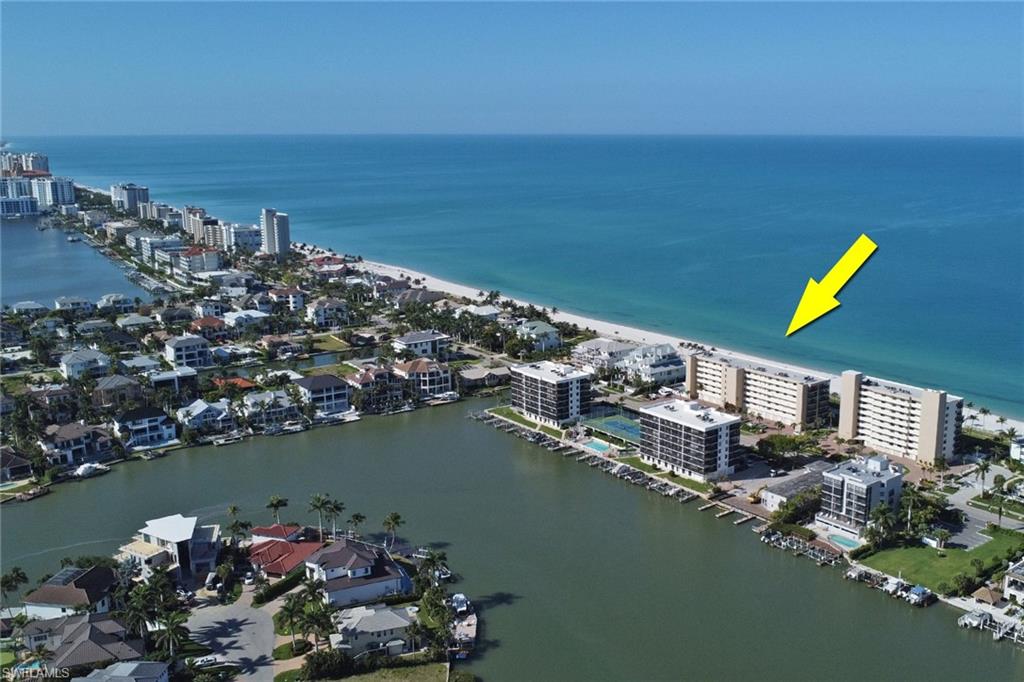 Waterfront property featuring direct beach access, multiple residential buildings, and a canal with boat dockage