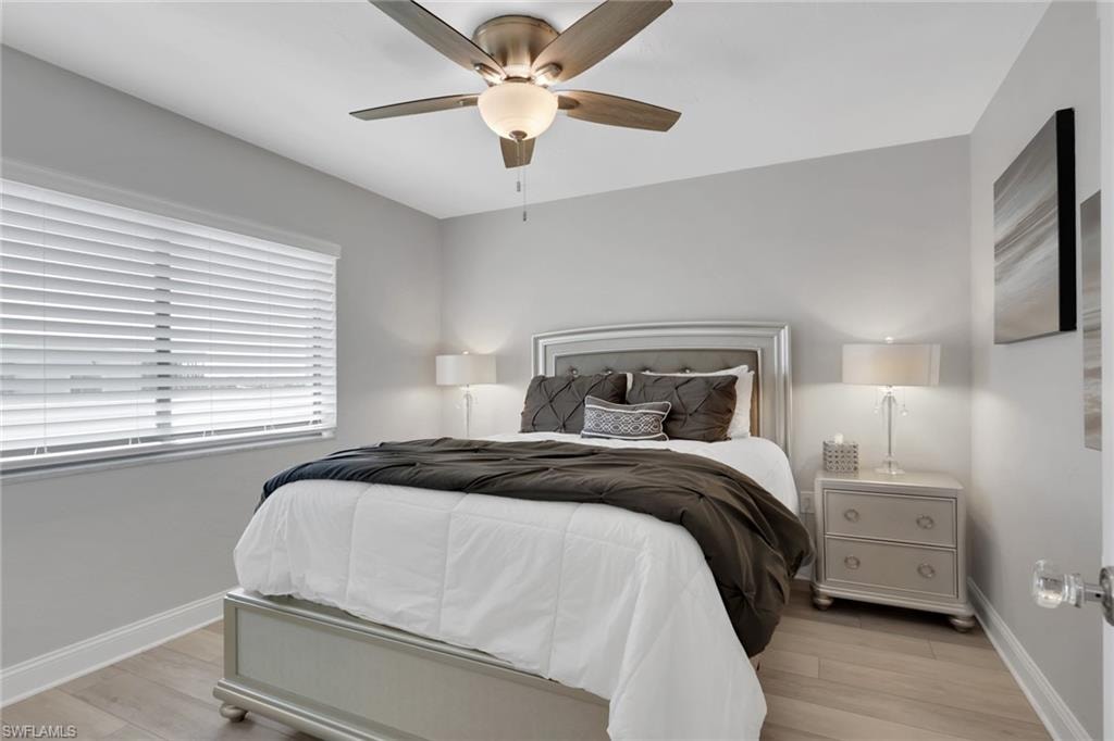 Interior space featuring light wood-finish flooring, a window with white horizontal blinds, and a ceiling fan with integrated lighting