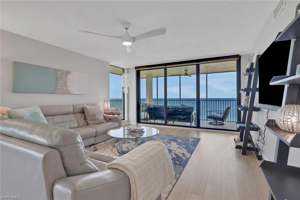 Living area featuring expansive sliding glass doors opening to a balcony with water scenery