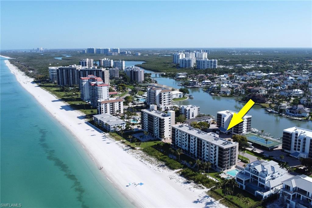 Coastal high-rise condominium with direct beach access, multiple balconies, a waterside pool, and a tennis court