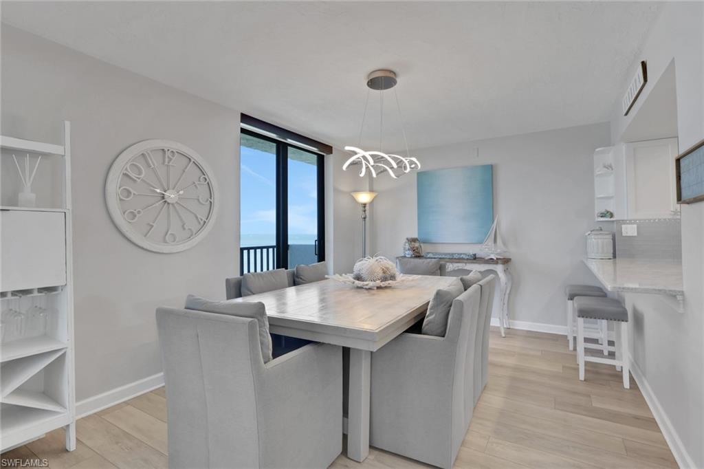 Dining area featuring light wood-finish flooring, a contemporary chandelier, and direct balcony access through sliding glass doors
