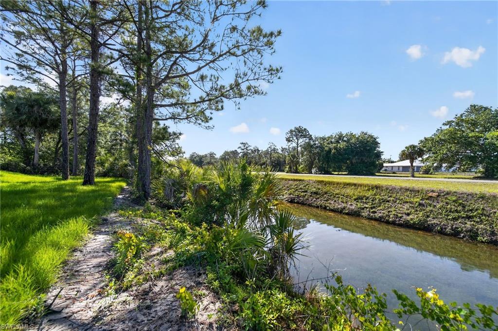 Canal frontage with lush green grass and mature trees