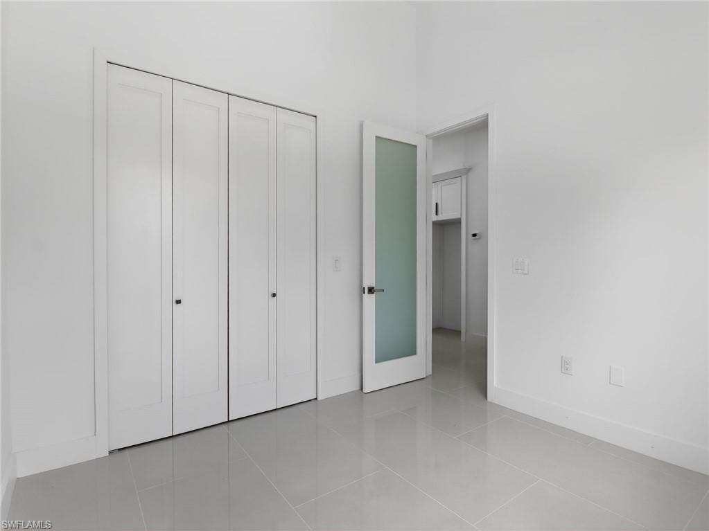 This room features light gray tiled flooring, crisp white walls, and white bi-fold closet doors
