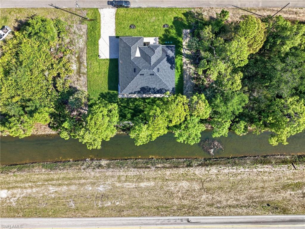 Aerial perspective highlighting a single-story residence with a dark shingle roof and a concrete driveway