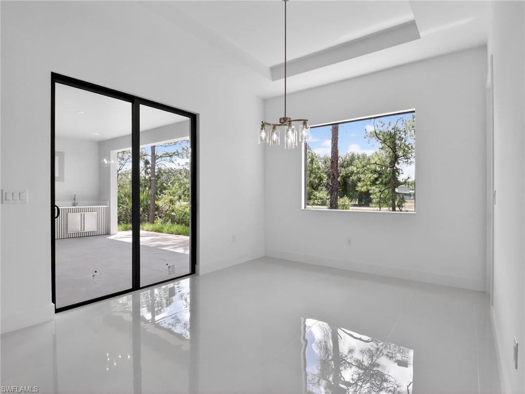 This room features bright white walls, polished floors, and a modern chandelier