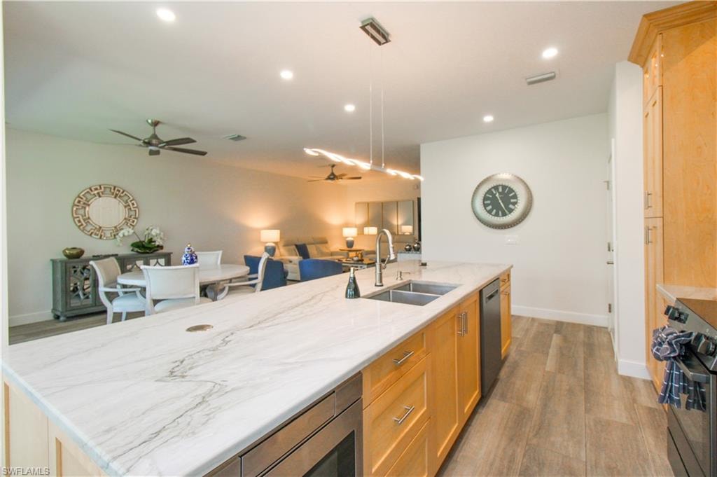 Kitchen with light hardwood / wood-style flooring, appliances with stainless steel finishes, decorative light fixtures, sink, and ceiling fan
