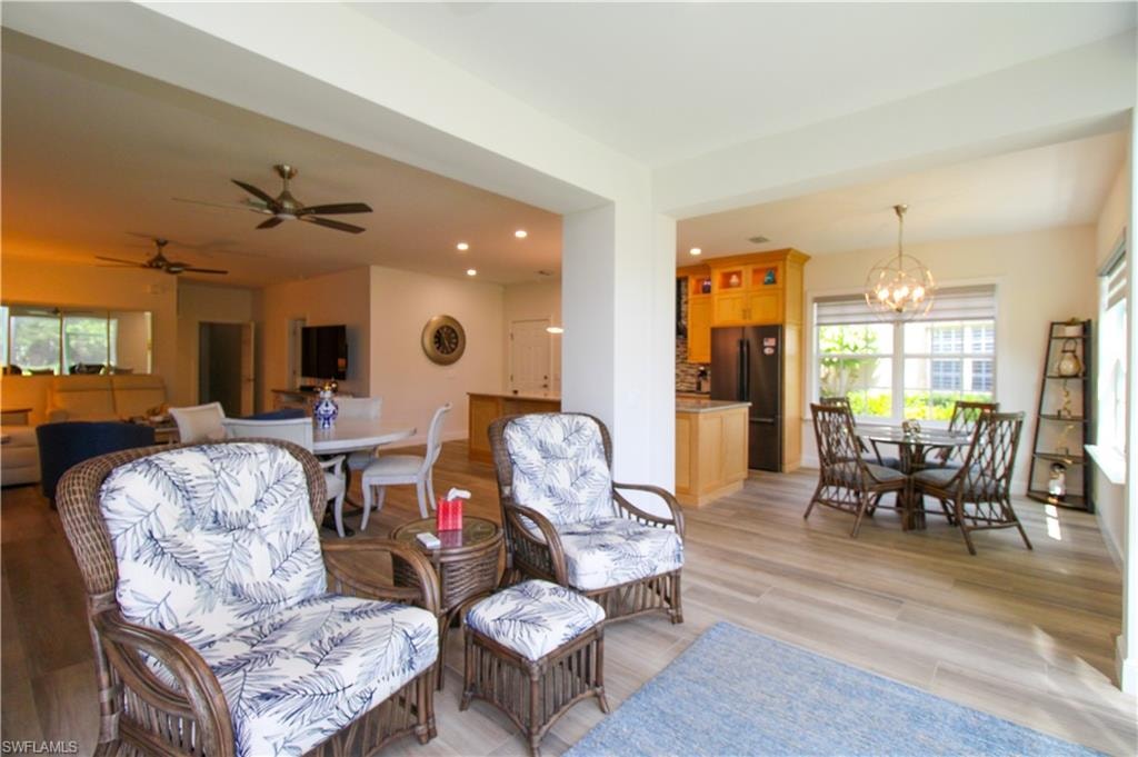Living room with light hardwood / wood-style floors and ceiling fan with notable chandelier