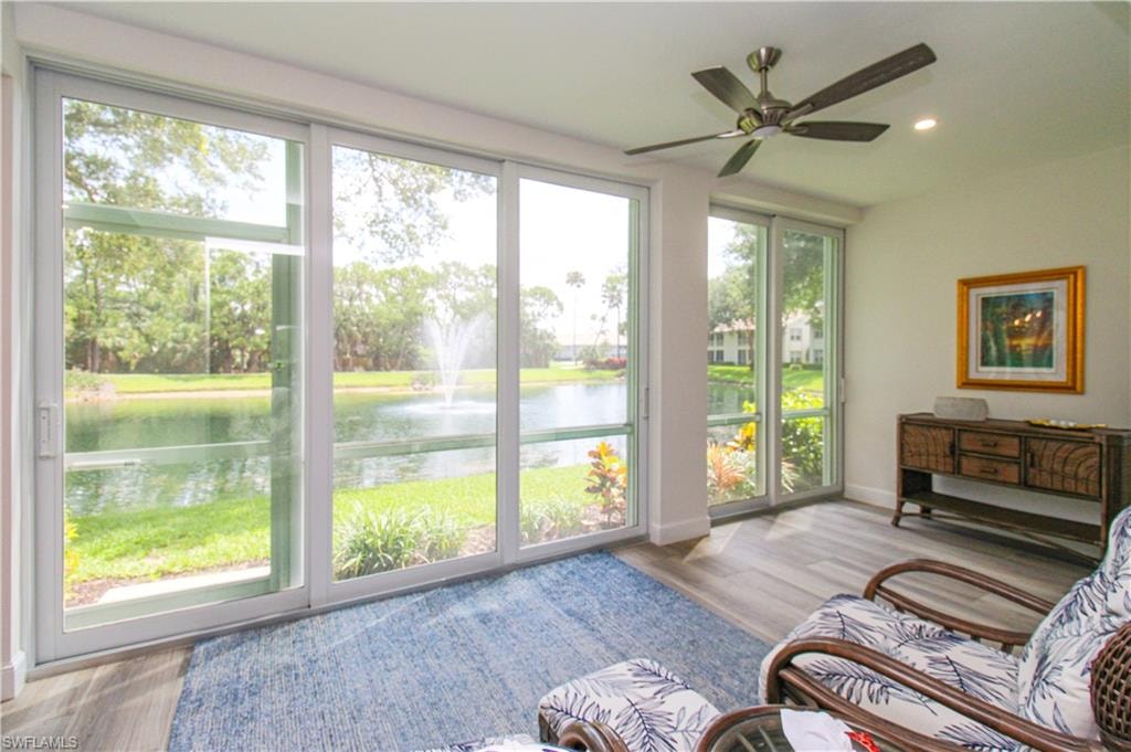 Sunroom with ceiling fan, a wealth of natural light, and a water view