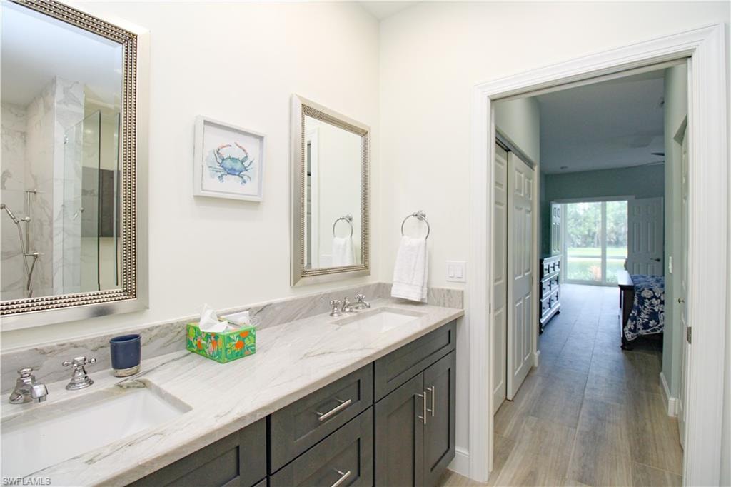 Bathroom featuring a shower with door, double sink vanity, and hardwood / wood-style floors