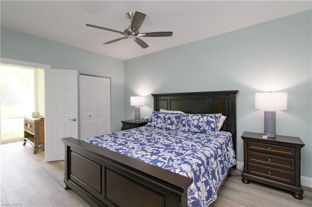 Bedroom with light hardwood / wood-style floors, a closet, ceiling fan, and multiple windows