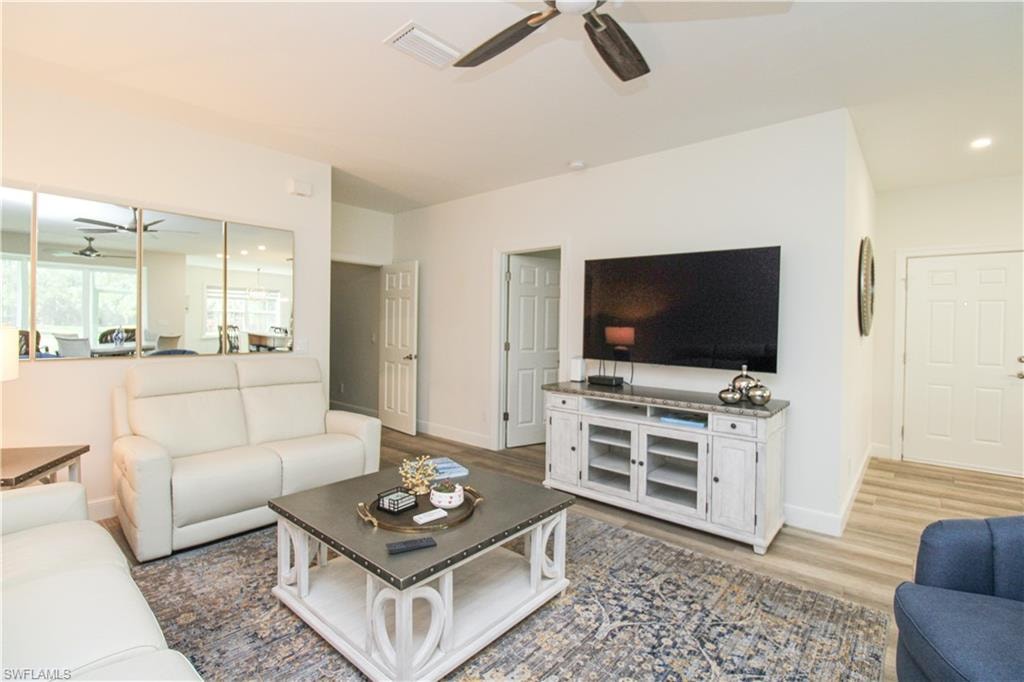 Living room with ceiling fan and hardwood / wood-style floors