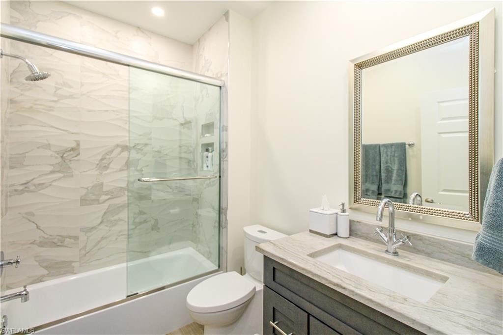 Full bathroom with shower / bath combination with glass door, toilet, and vanity