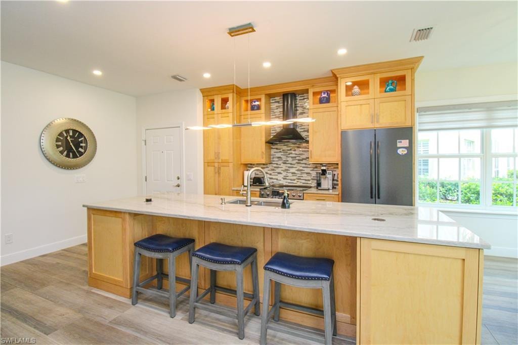 Kitchen featuring pendant lighting, a spacious island, backsplash, and stainless steel refrigerator