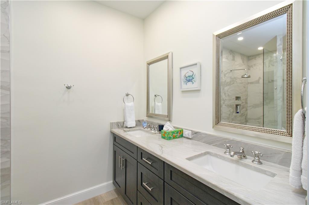 Bathroom featuring a shower with door and double sink vanity