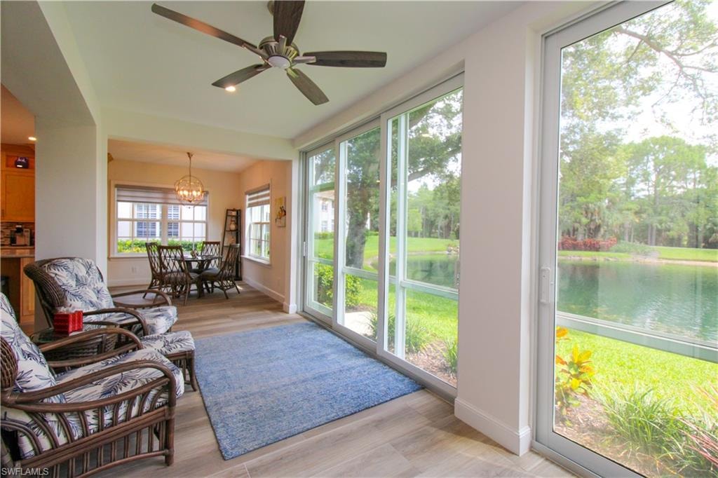 Sunroom / solarium with a water view and ceiling fan with notable chandelier