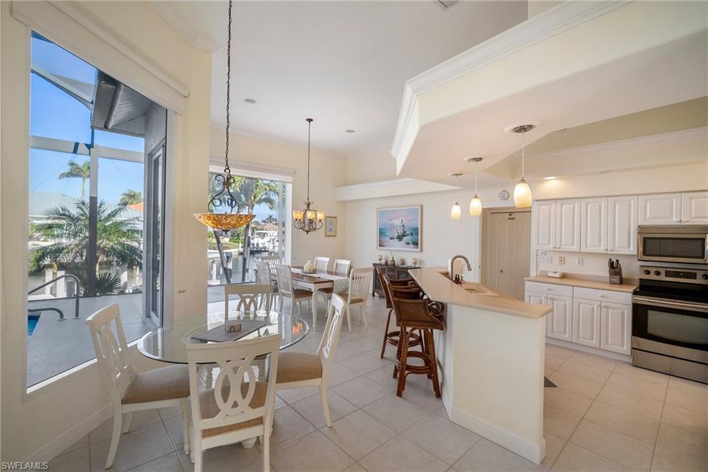 Kitchen with stainless steel appliances, an island with sink, pendant lighting, and white cabinetry