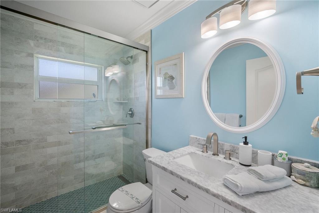Bathroom with vanity, ornamental molding, an enclosed shower, and toilet