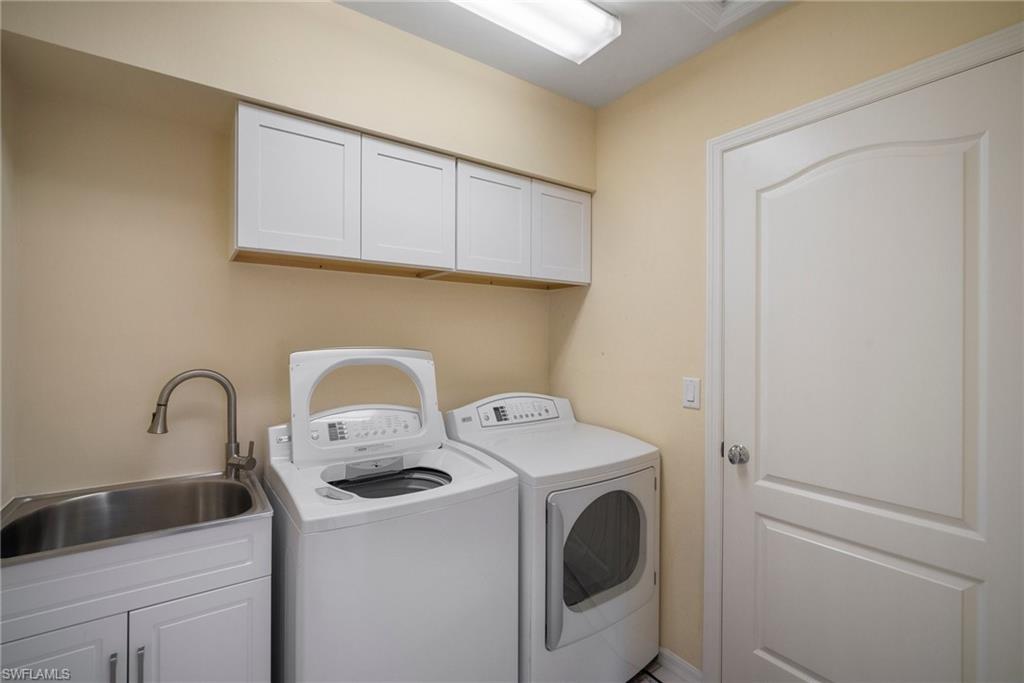 Clothes washing area with cabinets, separate washer and dryer, and sink