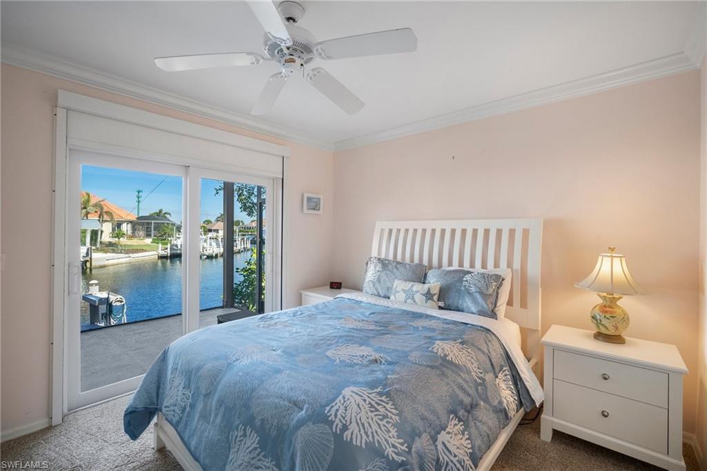 Carpeted bedroom featuring ornamental molding, a water view, access to exterior, and ceiling fan