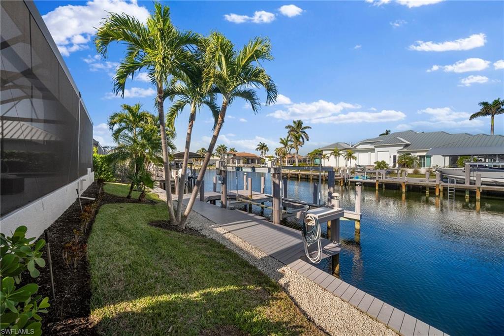Dock area with a lawn, a water view, and glass enclosure