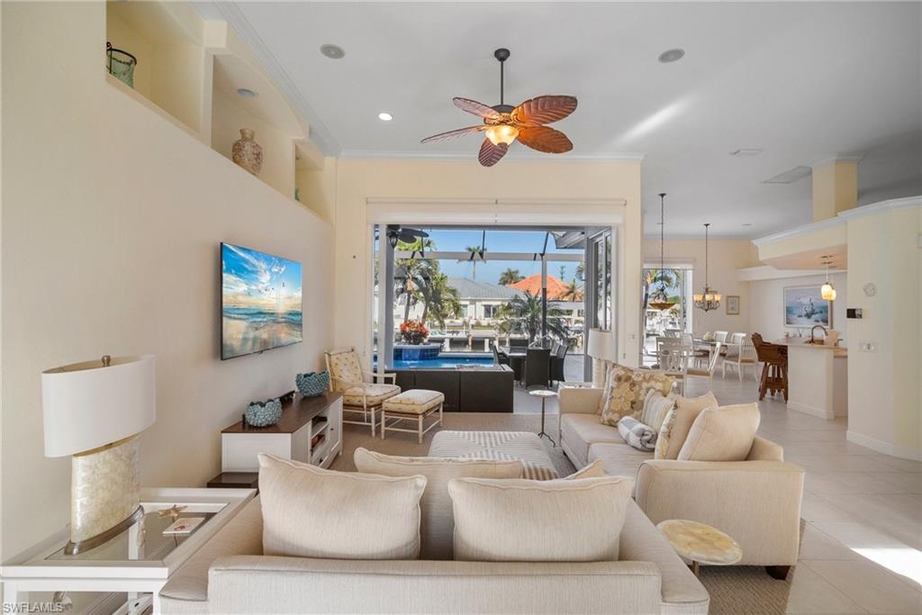 Tiled living room featuring ornamental molding and ceiling fan with notable chandelier