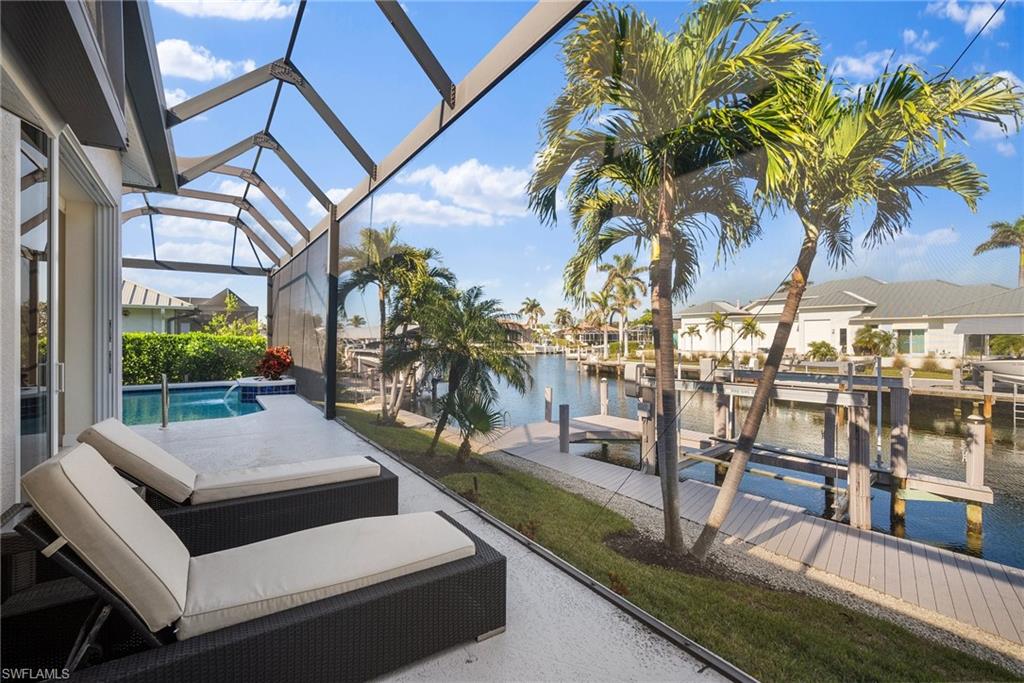 View of patio featuring a water view, a boat dock, pool water feature, and a lanai