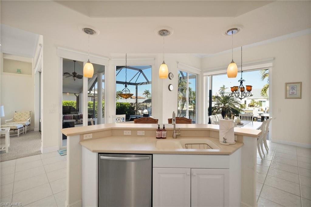 Kitchen with pendant lighting, sink, light tile patterned floors, dishwasher, and white cabinetry