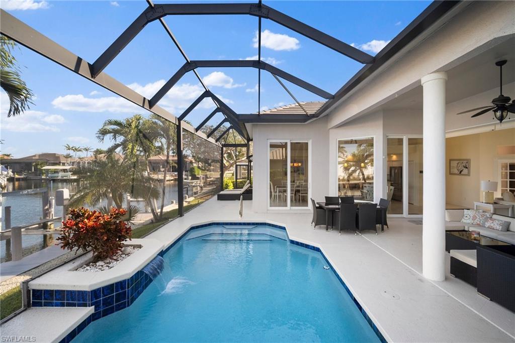View of pool with ceiling fan, outdoor lounge area, glass enclosure, a water view, and a patio area