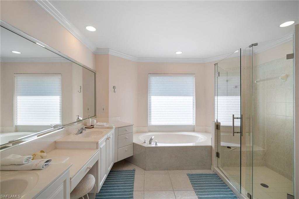 Bathroom with tile patterned flooring, vanity, ornamental molding, and plus walk in shower