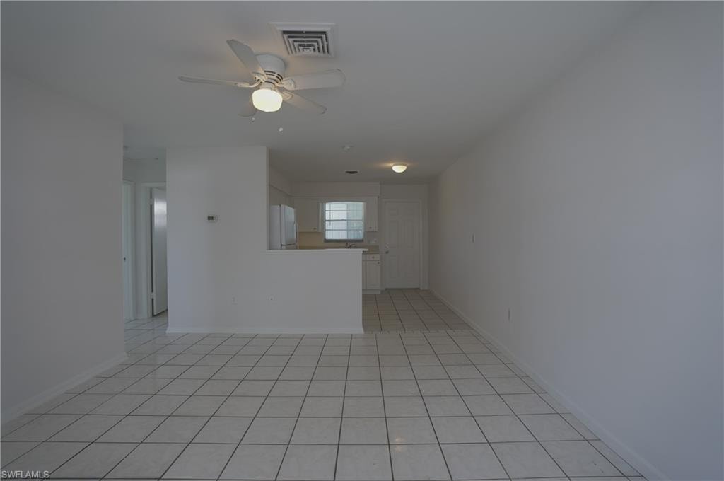 The living area features white tile flooring, a ceiling fan with integrated lighting, and white painted walls