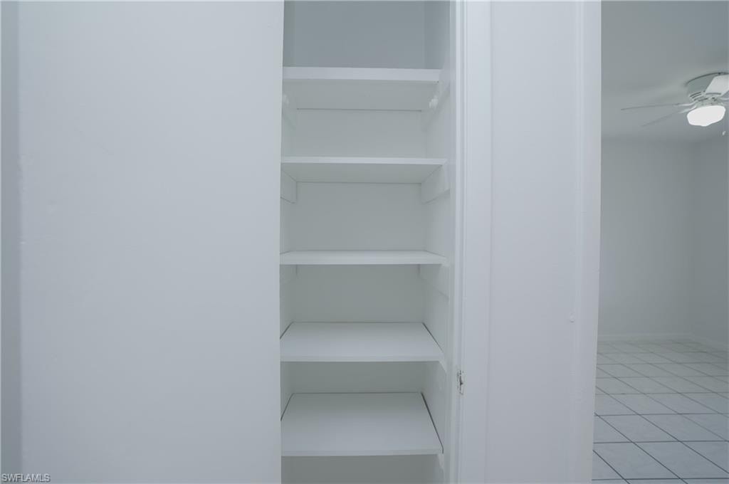 Built-in shelving unit providing storage space, with tile flooring and a ceiling fan visible in the background