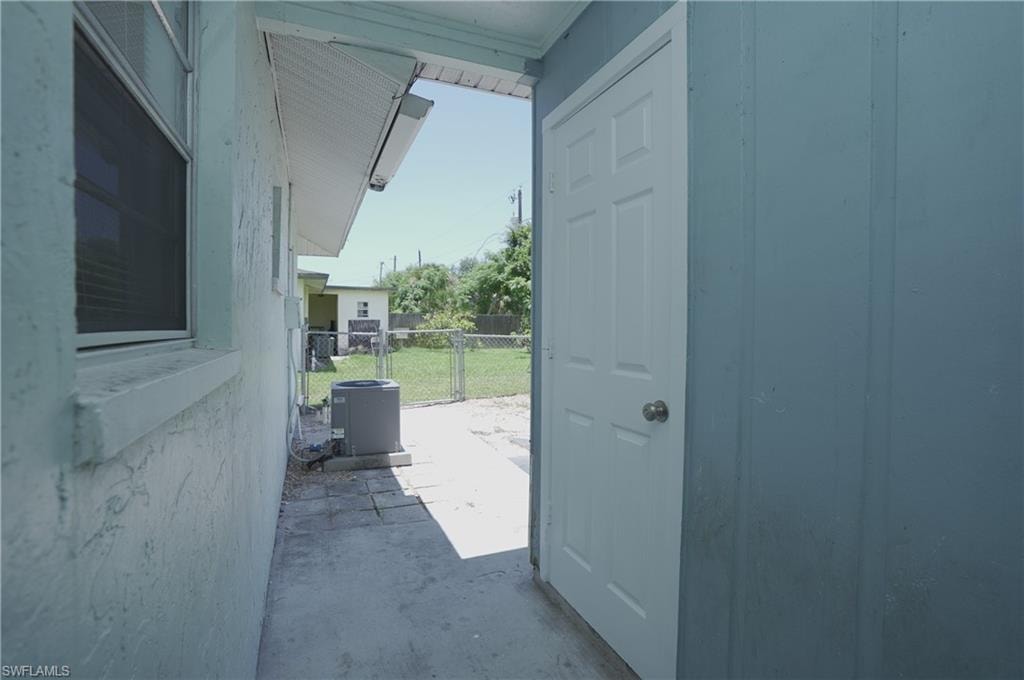 Exterior view of the property featuring a white door, a window with blinds, and an outdoor unit