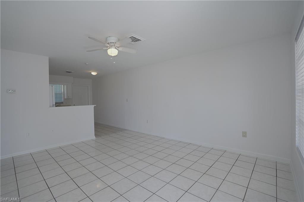 This living area features tile flooring, a ceiling fan with integrated lighting, and a window with blinds