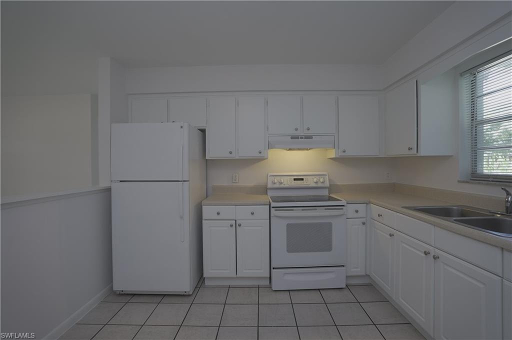 The kitchen features white cabinetry, a white refrigerator, a white electric range, and a double basin sink