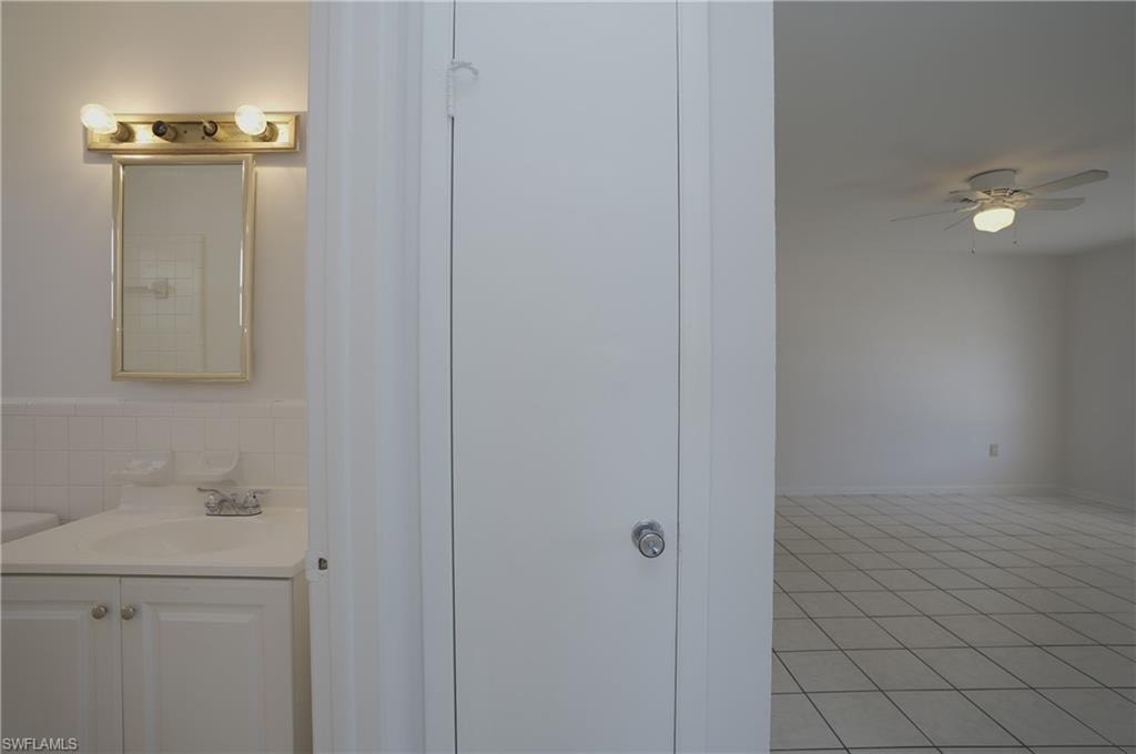 The property features a bathroom with a vanity, mirror, and overhead lighting fixture, and a separate room with tiled flooring and a ceiling fan