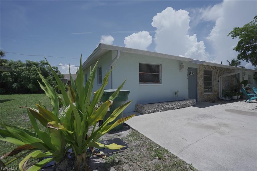 The property features a light-colored exterior with stone accents, a concrete driveway, and a well-maintained lawn area