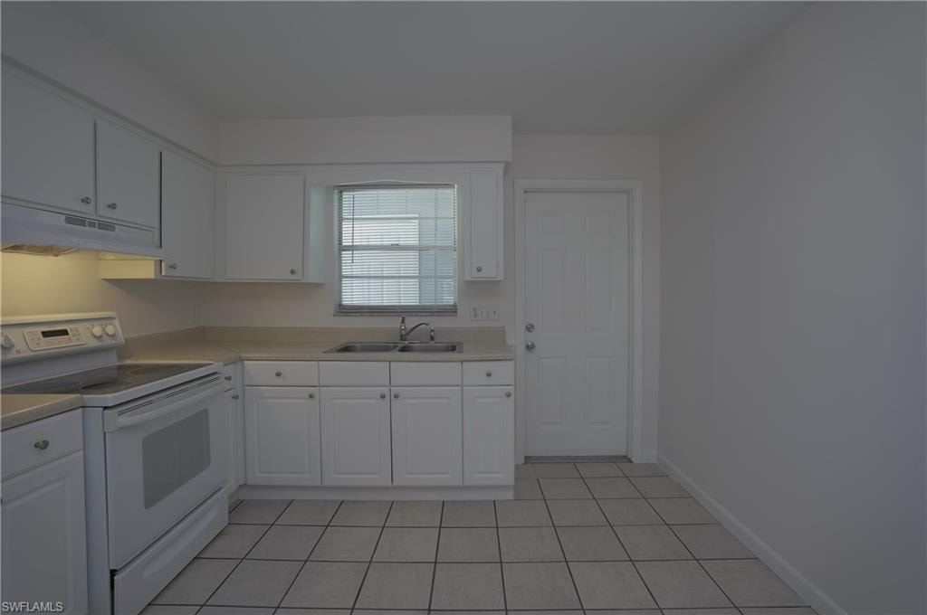 The kitchen features white cabinetry, a double basin sink, and a white electric range